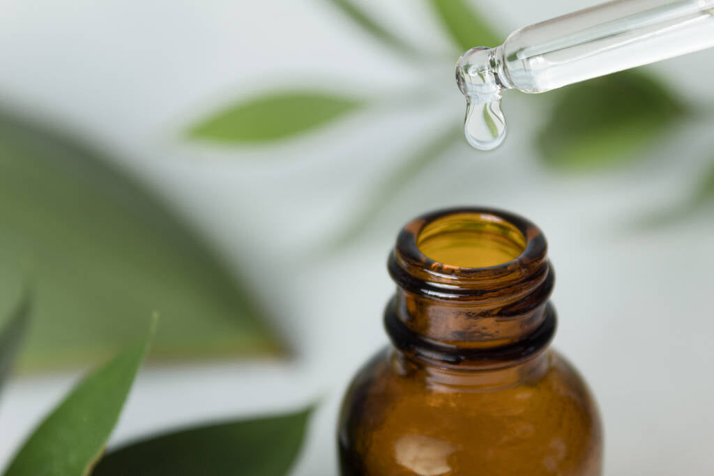 A drop of squalene serum flows from the pipette and drips into the bottle.