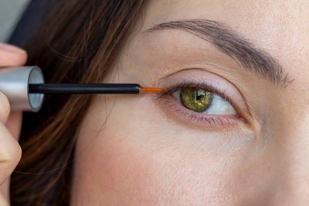 A woman applying eyelash growth serum