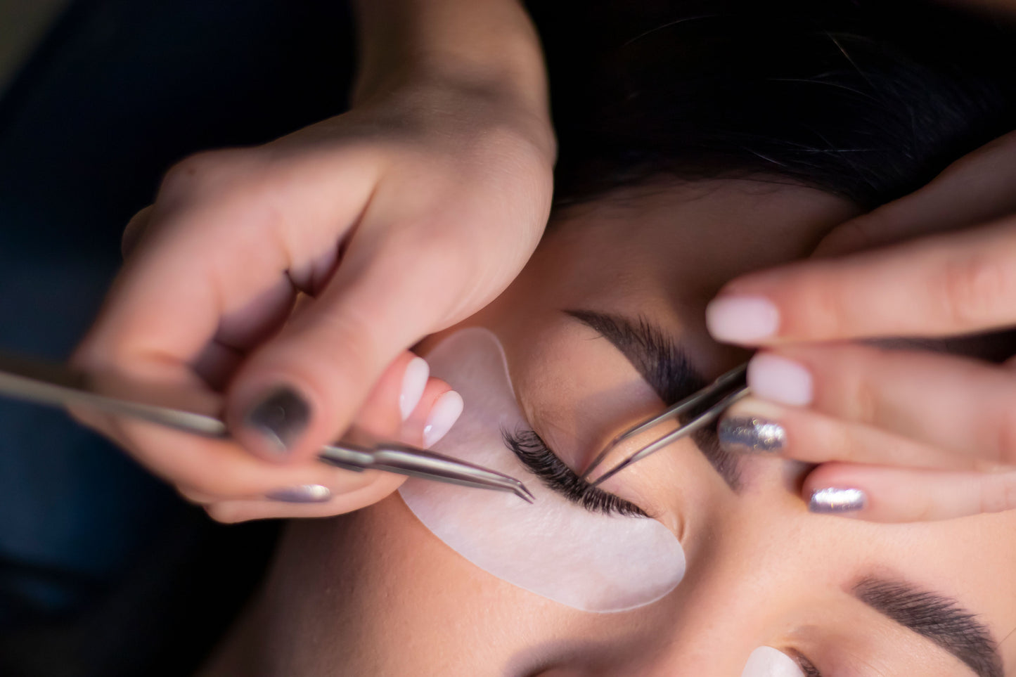  A woman getting eyelash extensions applied during a professional lash appointment.