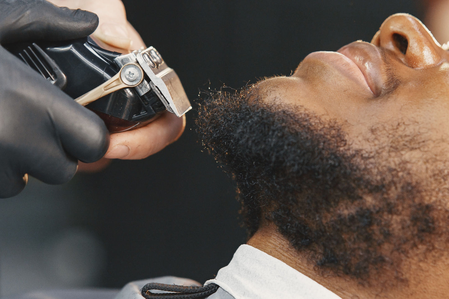A man with a curly beard getting a beard trim.
